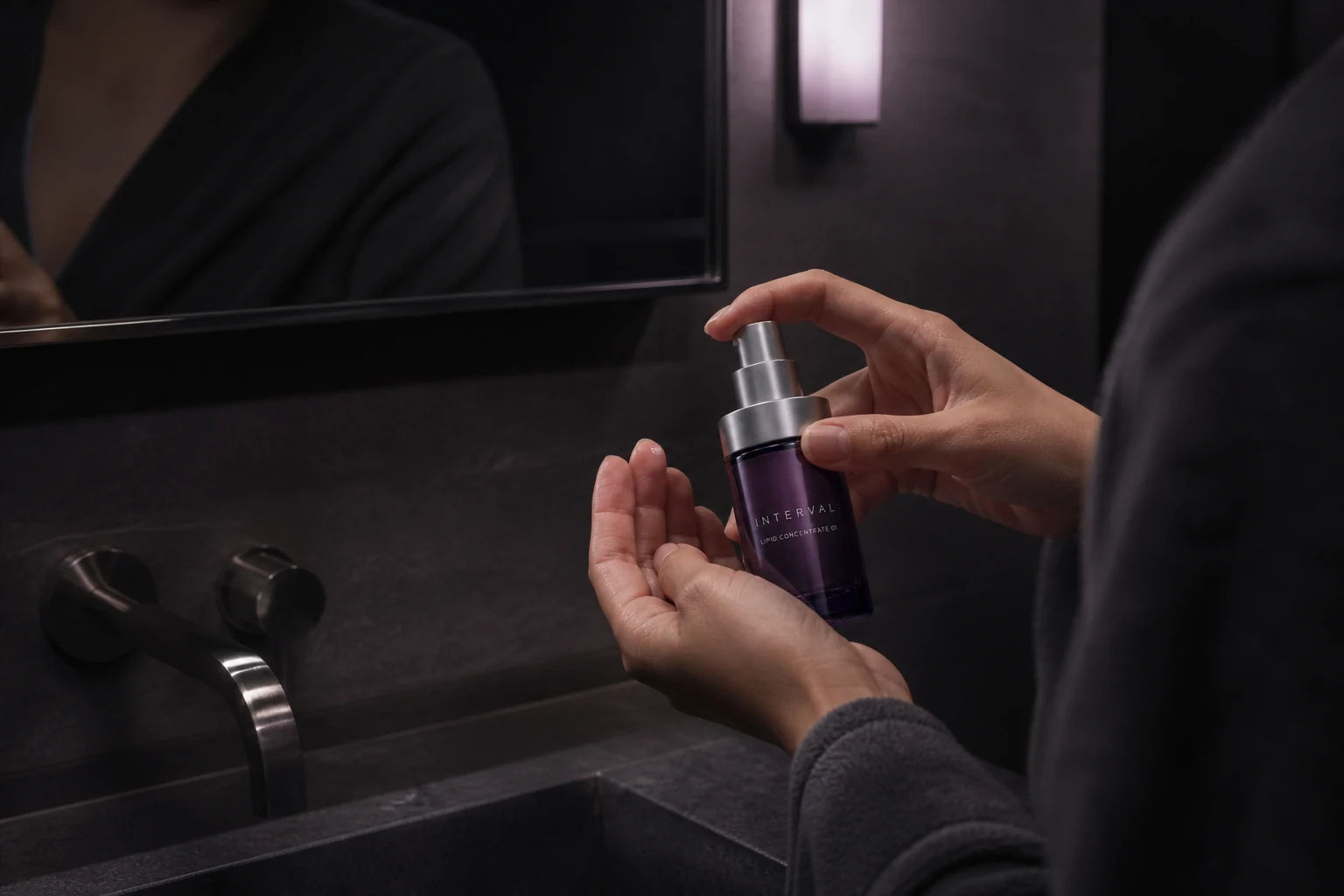 Hands dispensing INTERVAL concentrate in a dark bathroom